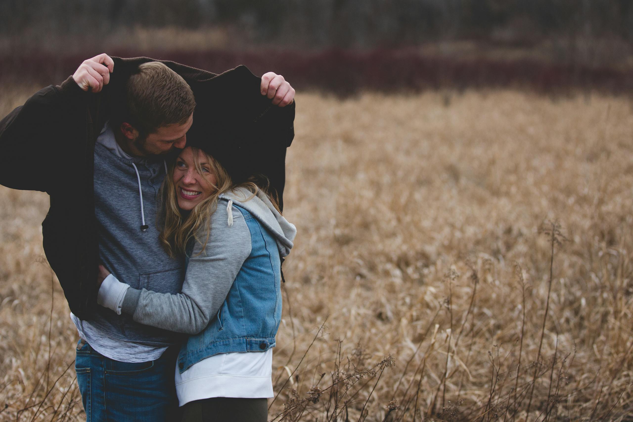 Man and Woman Hugging on Brown Field