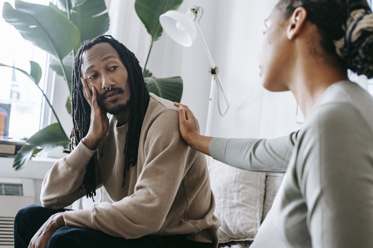 Ethnic psychologist touching black depressed clients shoulder