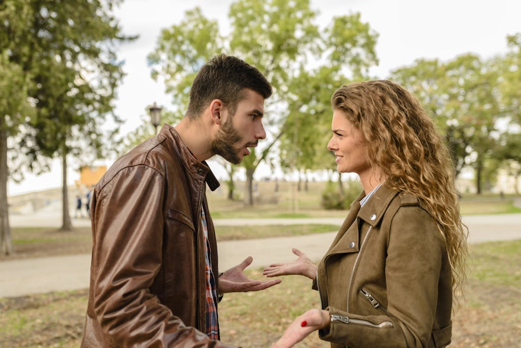 A couple having an argument outdoors, expressing frustration and conflict.