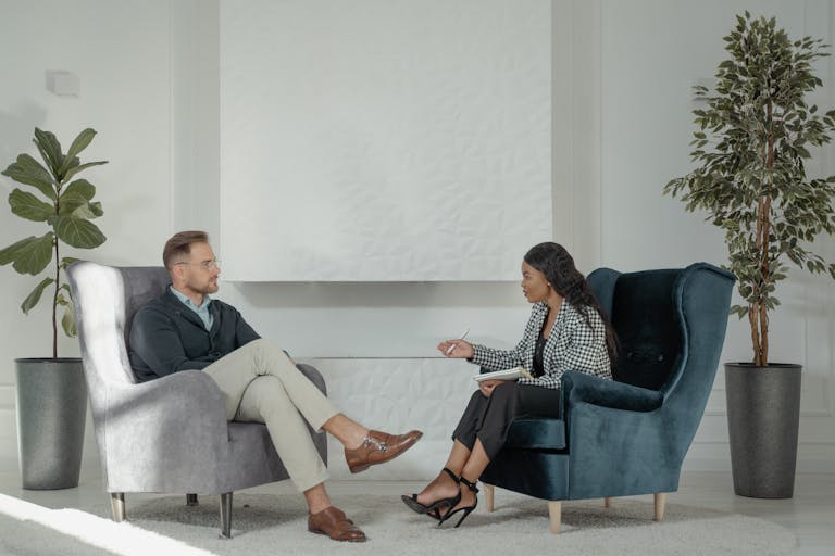 A therapist and patient engaged in conversation in a modern, stylish therapy office.