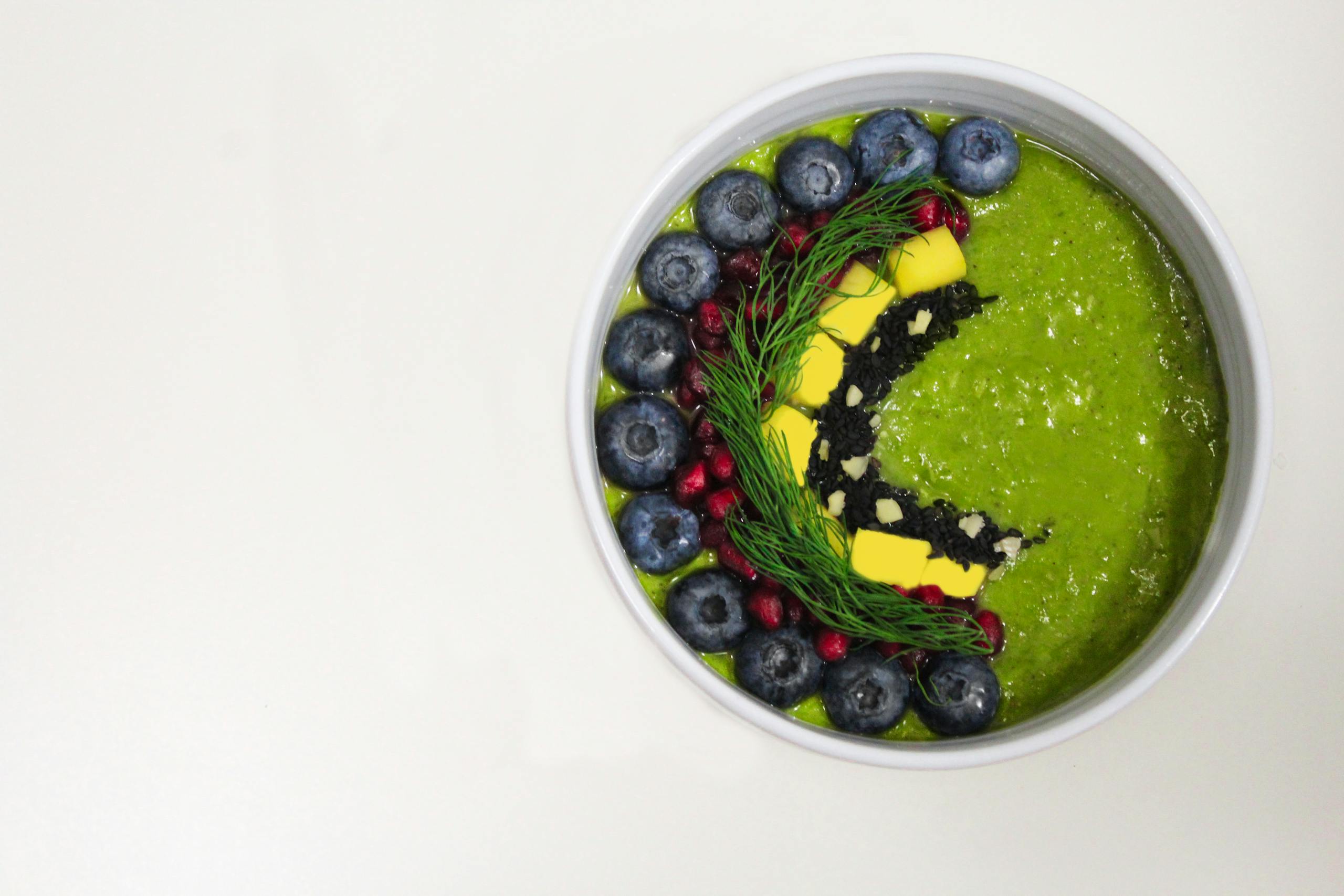 A vibrant green smoothie bowl decorated with blueberries and garnishes for a healthy breakfast.