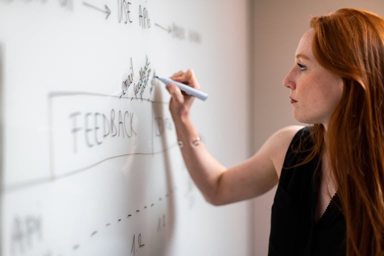 Focused woman writing on a whiteboard during a business planning session.