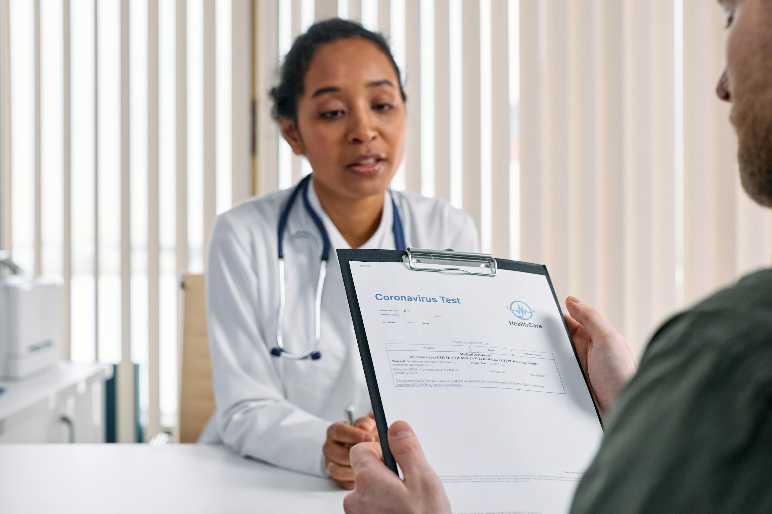 Doctor having a consultation with a patient over coronavirus test results in a medical office.