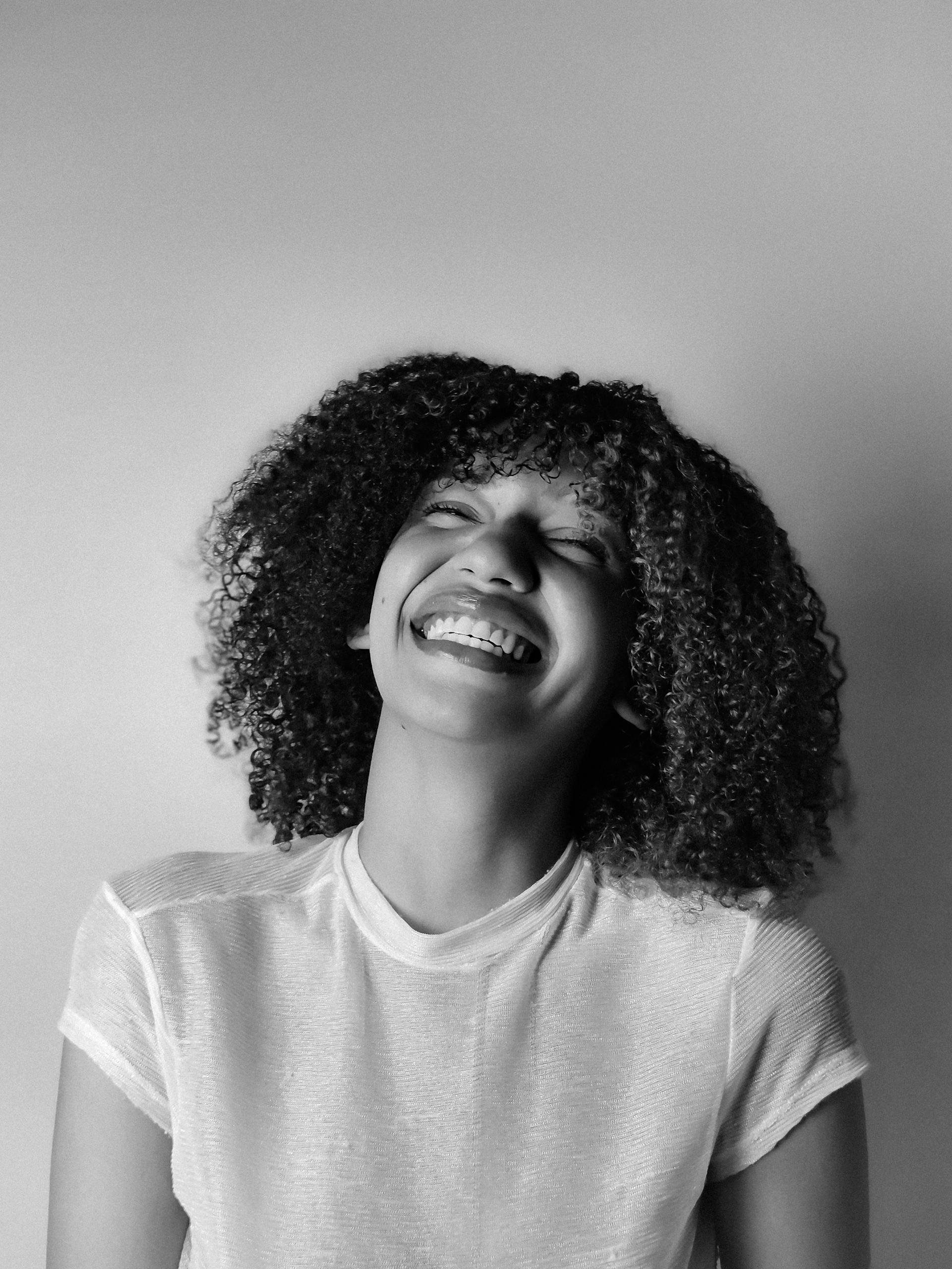 Black and white photo of a woman laughing joyfully, expressive and candid.