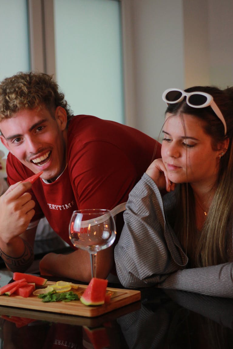 Two friends enjoying a casual indoor gathering with snacks and drinks.